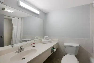 a bathroom with a sink and a toilet and a mirror at Essence Express Wayne in Wayne