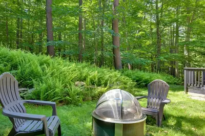 two chairs and a grill in a yard with trees at Sweetfern Gouldsboro Cabin Deck and Lake Access in Gouldsboro