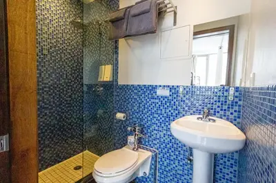 a blue tiled bathroom with a toilet and a sink at JG Sohotel in New York