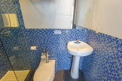 a blue tiled bathroom with a toilet and a sink at JG Sohotel in New York