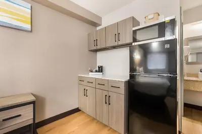 a kitchen with a stainless steel refrigerator and cabinets at HomeTowne Studios by Red Roof Princeton - Ewing/ Lawrenceville in Trenton