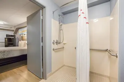 a bathroom with a shower and a bedroom at HomeTowne Studios by Red Roof Princeton - Ewing/ Lawrenceville in Trenton
