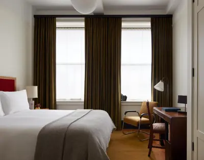 a bedroom with a bed and a desk and windows at Nine Orchard in New York