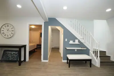 a hallway with a clock and stairs with a bench at A gorgeous home, 5BR-2BT, perfect for your family! in Tobyhanna