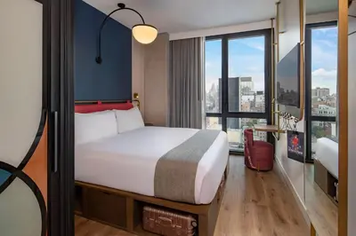 a hotel room with a bed and a large window at Moxy NYC Lower East Side in New York