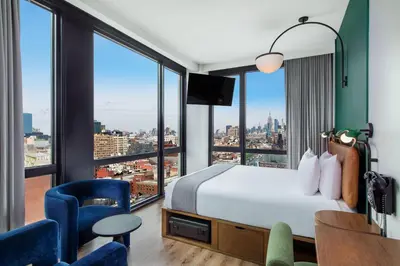 a hotel room with a bed and a desk and chairs at Moxy NYC Lower East Side in New York