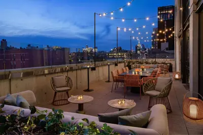 a rooftop patio with tables and chairs and lights at Moxy NYC Lower East Side in New York