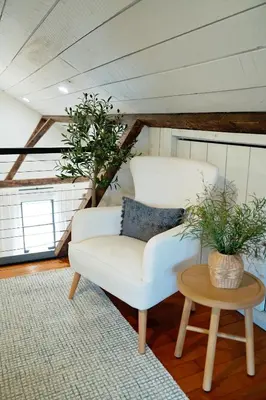 a living room with a white chair and a table at The Loft at Woodhaven Hideaway in Myerstown