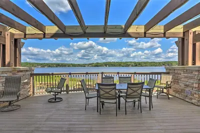 a deck with a table and chairs and a view of a lake at Game Room and Fire Pit Tree-Lined Pocono Lake Cabin in Pocono Lake