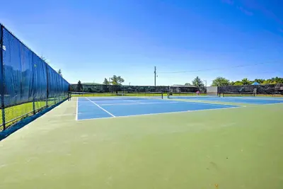a tennis court with two people playing tennis at Game Room and Fire Pit Tree-Lined Pocono Lake Cabin in Pocono Lake