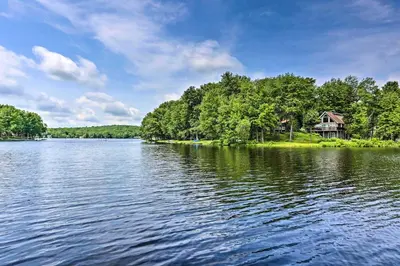 a house on the shore of a large lake at Game Room and Fire Pit Tree-Lined Pocono Lake Cabin in Pocono Lake
