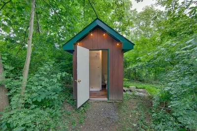 a small shed with a door in the woods at Tranquil Creekside Cabin in Dutch Country! in Narvon