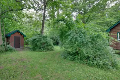 a yard with a red shed and trees and grass at Tranquil Creekside Cabin in Dutch Country! in Narvon