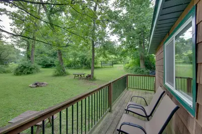 a porch with two benches and a picnic table at Tranquil Creekside Cabin in Dutch Country! in Narvon