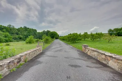 a road with a stone bridge over a field at Tranquil Creekside Cabin in Dutch Country! in Narvon