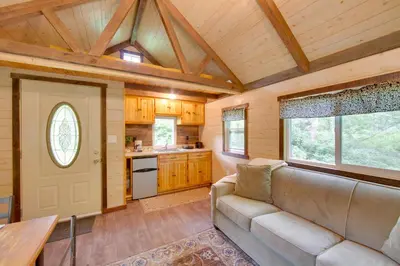a living room with a couch and a kitchen at Tranquil Creekside Cabin in Dutch Country! in Narvon