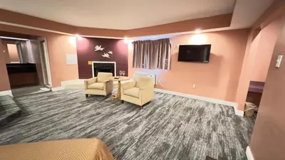 a living room with two chairs and a table and a tv at Inn of the Dove Harrisburg-Hershey Romantic Suites in Harrisburg