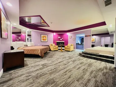 a hotel room with a large bed and purple walls at Inn of the Dove Harrisburg-Hershey Romantic Suites in Harrisburg