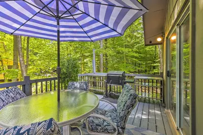 a table and chairs on a porch with an umbrella at Wraparound Deck Big Bass Lake Home in Gouldsboro in Gouldsboro