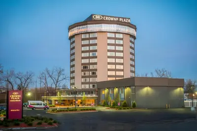 a building with a car parked in a parking lot at Crowne Plaza Saddle Brook by IHG in Saddle Brook