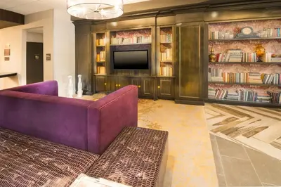 a living room with a purple couch and a tv at Crowne Plaza Saddle Brook by IHG in Saddle Brook
