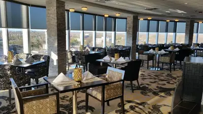 a restaurant with tables and chairs and large windows at Crowne Plaza Saddle Brook by IHG in Saddle Brook
