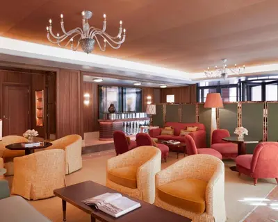 a waiting room with chairs and tables and a chandelier at Fouquet's New York in New York