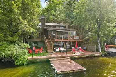 a house on the water with chairs and a dock at Harmony Haven in Lake Harmony