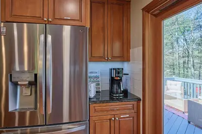 a kitchen with a stainless steel refrigerator and wooden cabinets at Spacious Catskills Serenity nearby Delaware River Gap w Game Rm Pet Friendly and Fenced Yard in Glen Spey