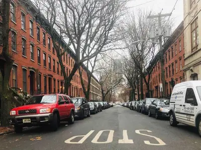 a street with cars parked on the side of the road at 1850s historic Row House 7min train to NYC with private backyard in Jersey City