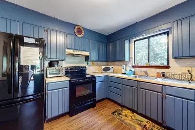 a kitchen with blue cabinets and a black refrigerator at The Burrow in Jim Thorpe