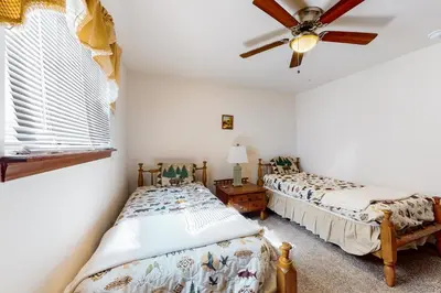 two beds in a room with a ceiling fan at The Burrow in Jim Thorpe