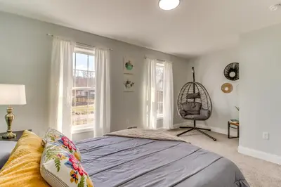 a bedroom with a bed and a chair and windows at Hot Tub! Family Tobyhanna Getaway 12 Mi to Slopes in Tobyhanna