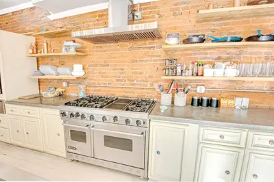 a kitchen with a stove and a brick wall at Spacious Oasis - Parking, Private Patio & Roofdeck in Philadelphia