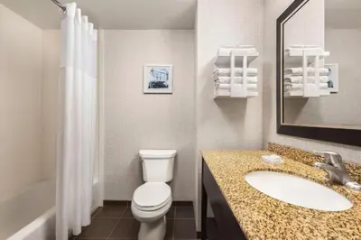 a bathroom with a toilet and a sink and a mirror at Hampton Inn & Suites York South in York