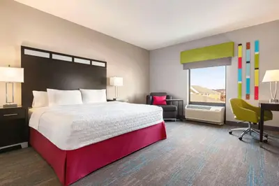 a hotel room with a bed and a desk and a window at Hampton Inn & Suites York South in York
