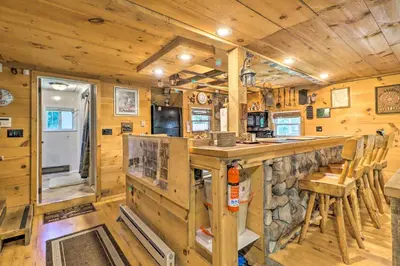 a log cabin kitchen with a counter and a bar at Secluded and Quiet Pocono Mountain Cabin with Hot Tub! in Kunkletown