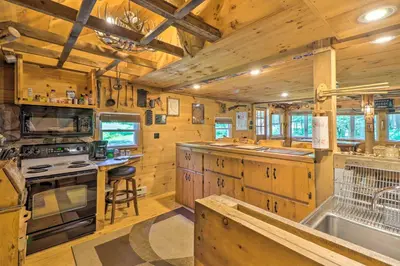 a kitchen with wooden cabinets and a stove top oven at Secluded and Quiet Pocono Mountain Cabin with Hot Tub! in Kunkletown