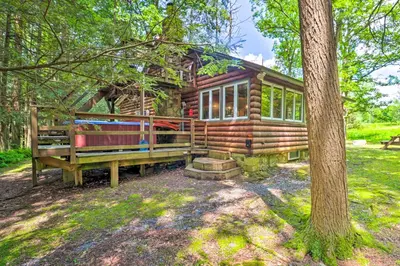 a log cabin in the woods with a tree at Secluded and Quiet Pocono Mountain Cabin with Hot Tub! in Kunkletown