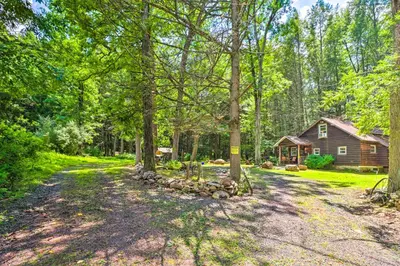 a home for sale in the woods with a log cabin at Secluded and Quiet Pocono Mountain Cabin with Hot Tub! in Kunkletown