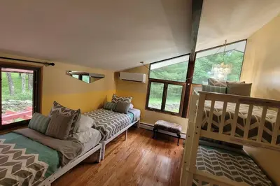 a room with a bed and a bunk bed and windows at Sunset Estate in the Catskills in Monticello