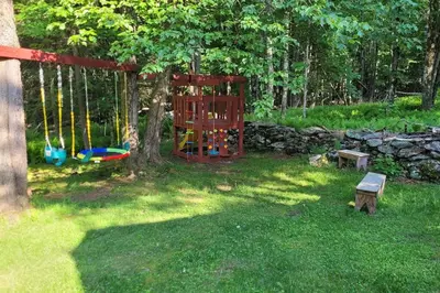 a playground in a yard with a tree and a swing at Sunset Estate in the Catskills in Monticello