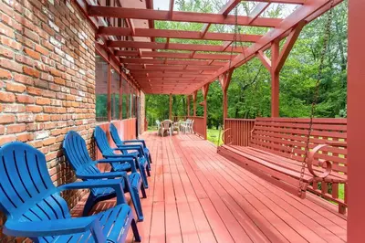 a wooden deck with blue chairs and a bench at Sunset Estate in the Catskills in Monticello