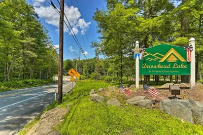 a sign for aacostimated bridge with two american flags at Romantic Pocono house - stream, lake, beach, pool, firepit in Locust Lakes Village