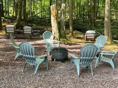 a group of chairs sitting around a fire pit at Romantic Pocono house - stream, lake, beach, pool, firepit in Locust Lakes Village