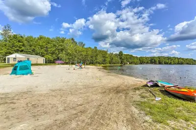 a beach with a tent and boats on the shore at Romantic Pocono house - stream, lake, beach, pool, firepit in Locust Lakes Village