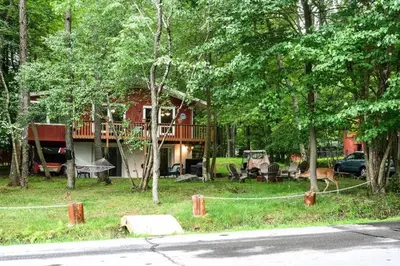 a house in the woods with a yard with trees at Peaceful Pocono Lakefront, beach, pools, firepit, pets in Arrowhead Lake
