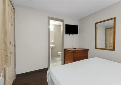 a bedroom with a bed and a mirror and a bathroom at Edison Motor Lodge in Edison