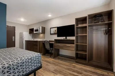 a room with a bed and a desk with a television at WoodSpring Suites South Brunswick - Princeton in Monmouth Junction