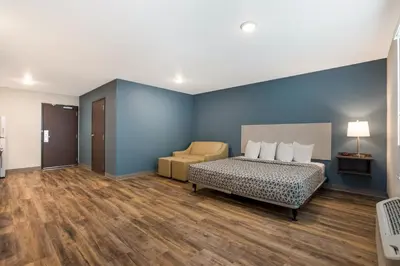 a bedroom with blue walls and a bed and a chair at WoodSpring Suites South Brunswick - Princeton in Monmouth Junction